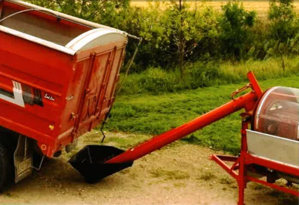 une vis utilitaire de manutention de grain qui rempli avec un fond forêt
